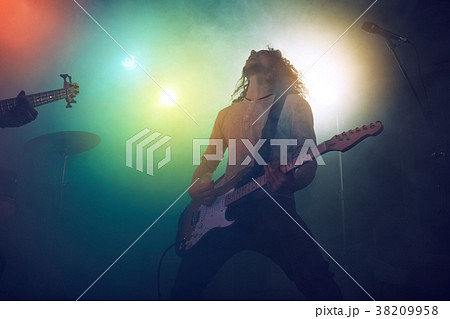 Rock band performs on stage. Guitarist, bass guitar and drums. 38209958
