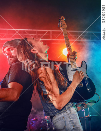 Rock band performs on stage. Guitarist, bass guitar and drums. 38209985