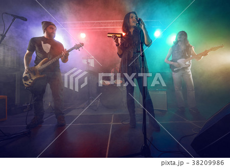Rock band performs on stage. Guitarist, bass guitar and drums. 38209986