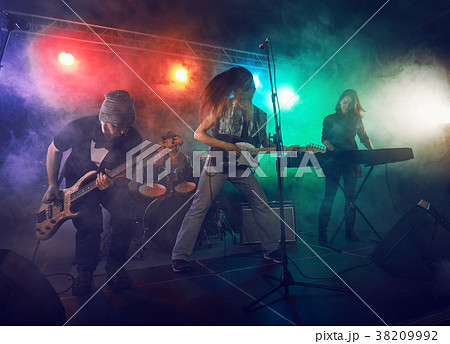 Rock band performs on stage. Guitarist, bass guitar and drums. Rock band performs on stage. Guitarist, bass guitar and drums. 38209992