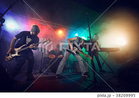 Rock band performs on stage. Guitarist, bass guitar and drums. Rock band performs on stage. Guitarist, bass guitar and drums. 38209995