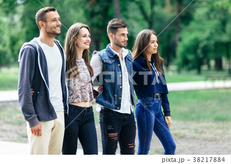Four young smiling friends relax in park 38217884