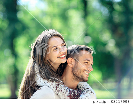 Loving couple man and woman having fun piggybacking in park 38217993
