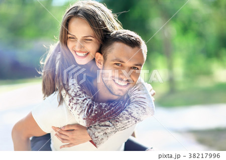 Man carrying his girlfriend on the back. Happy laughing couple 38217996