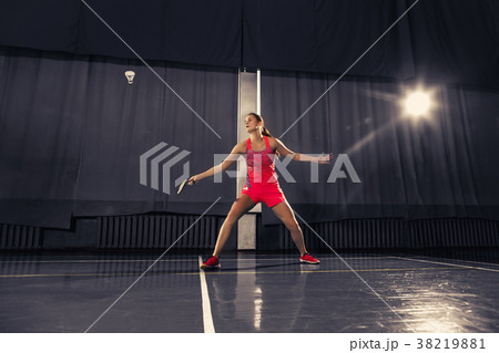 Young woman playing badminton at gym Young woman playing badminton at gym 38219881