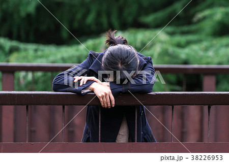 手すりにもたれて落ち込む女性 38226953