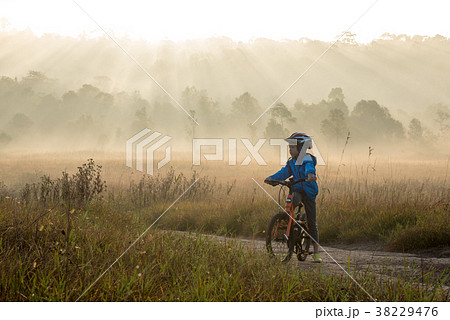 Boy rides a bicycle in the sunrise 38229476