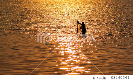 Fisherman with net in sea with sunset reflection Fisherman with net in sea with sunset reflection 38240541
