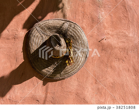 Straw hat hanging on textured clay wall Straw hat hanging on textured clay wall 38251808