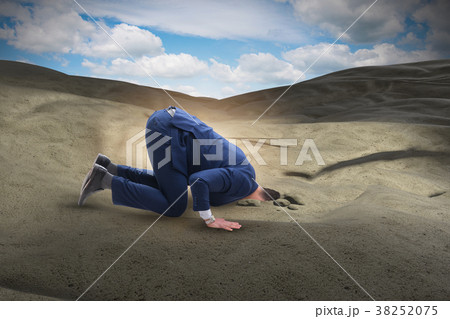 Businessman hiding his head in sand escaping from 38252075
