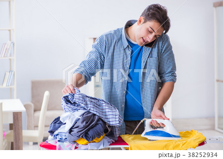 Young man husband doing clothing ironing at home Young man husband doing clothing ironing at home 38252934