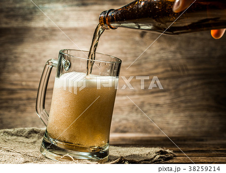 Foamy beer from bottle poured into mug 38259214