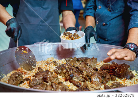 Two cooks in uniform prepare Uzbek pilaf from lamb 38262979