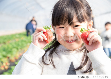 笑顔でいちごを持つ女の子の写真素材