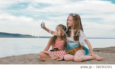 Two teenage are sitting on a sandy beach, on the 38293201