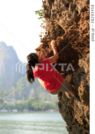 Young woman rock climber climbing on seaside cliff 38293458