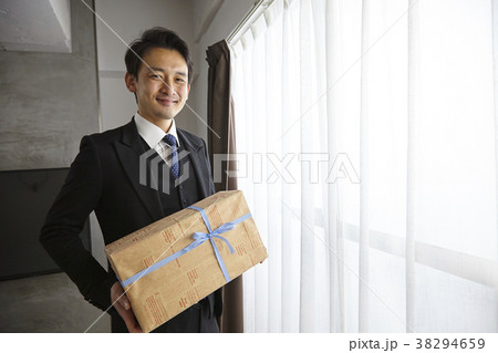 プレゼントを渡すお洒落なビジネスマン プレゼントを渡すお洒落なビジネスマン 38294659