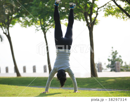 woman practice handstand on park meadow 38297314