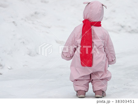 Small child in pink overalls with bunny ears lies 38303451