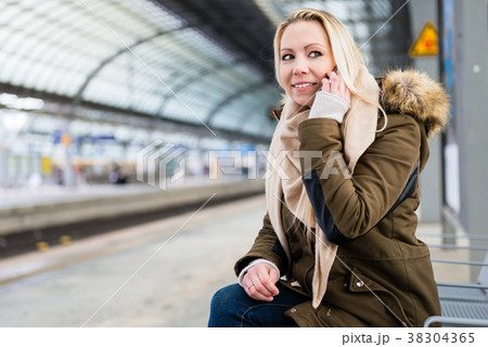 Woman using her phone while waiting for train on Woman using her phone while waiting for train on 38304365