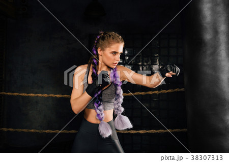 Young woman trains in boxing ring with heavy Young woman trains in boxing ring with heavy 38307313