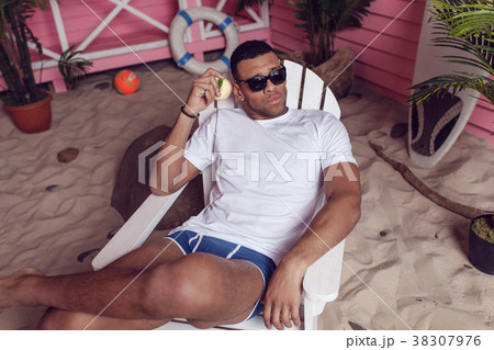 Sexy man in a white T-shirt is sitting on a wooden 38307976