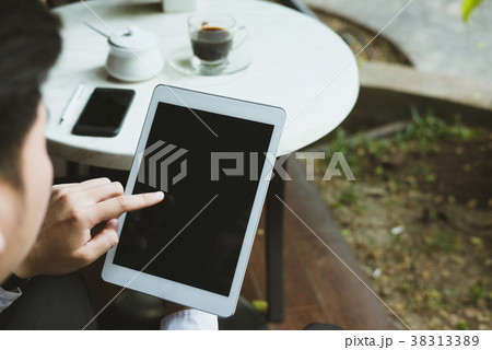businessman in suit holding touchpad while sitting at cafe. young asian startup man using digital tablet for work at coffee shop businessman in suit holding touchpad while sitting at cafe. young asian startup man using digital tablet for work at coffee shop 38313389