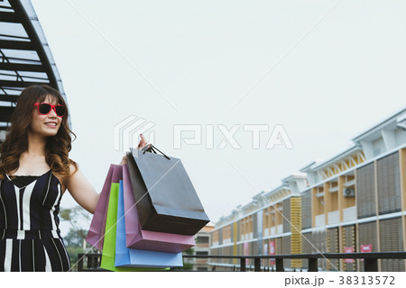 happy woman holding colorful shopping bag outdoors. shopaholic lady walking in city. shopper enjoy buying. consumerism concept 38313572