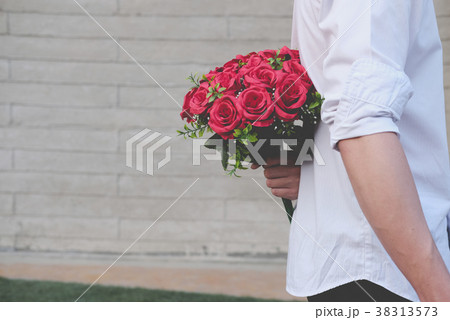 man holding bouquet of red roses behind his back. boyfriend surprise girlfriend with flower in valentine's day. celebrate anniversary, love, relationship concept man holding bouquet of red roses behind his back. boyfriend surprise girlfriend with flower in valentine's day. celebrate anniversary, love, relationship concept 38313573