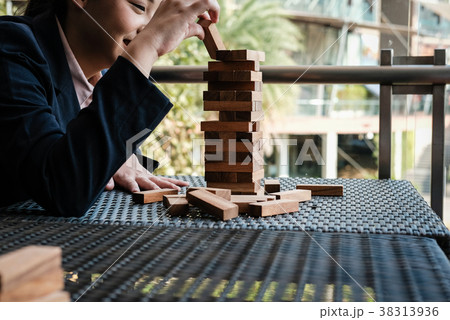 hand placing wood block on tower. growth, risk & strategy in business. 38313936