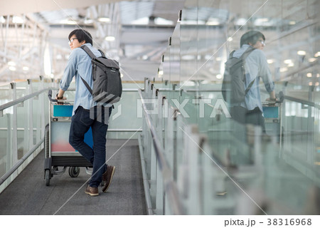 young asian man walking with trolley in airport young asian man walking with trolley in airport 38316968