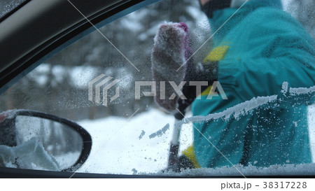 Young man brushes off the snow from the parked car 38317228