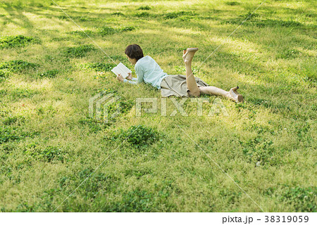 公園の芝生で読書をする女性の写真素材