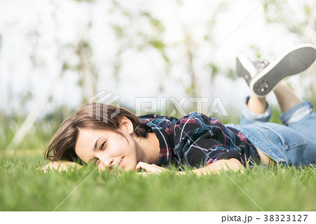 芝生に寝そべる笑顔の女性の写真素材
