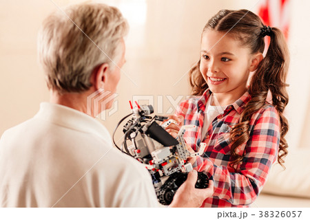 Smiling girl looking at grandfather holding robot Smiling girl looking at grandfather holding robot 38326057