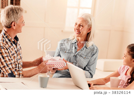Mindful senior man surprising his wife with gift 38326114