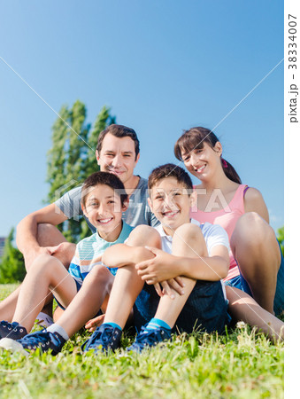 Family dressed in white in park in summer sitting 38334007