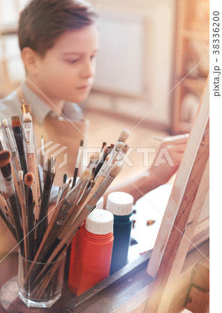 Serious teen boy painting masterpiece in studio 38336200