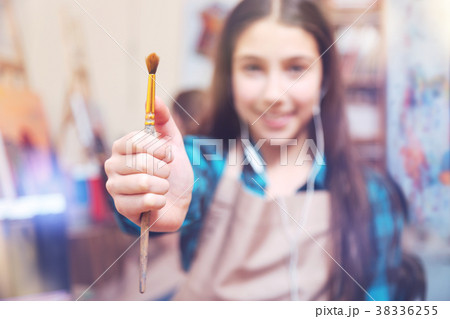 Cheerful girl holding painting brush and smiling 38336255