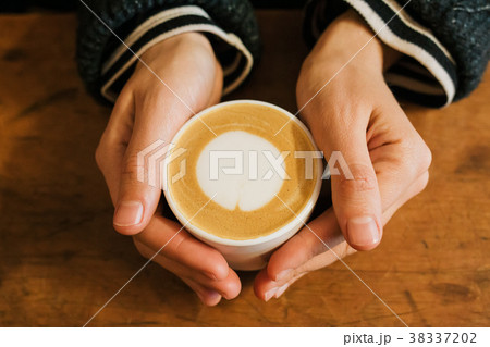 Girl holding a hot cup of coffee Girl holding a hot cup of coffee 38337202