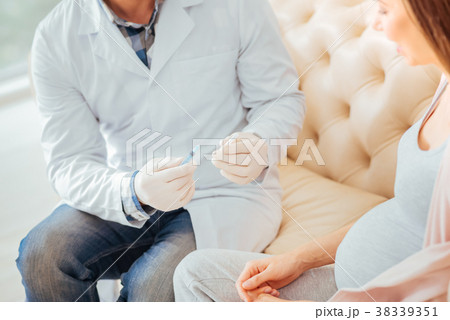 Careful qualified medic sitting and holding the 38339351