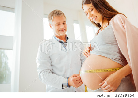 Joyful skilled medic standing and measuring womans 38339354