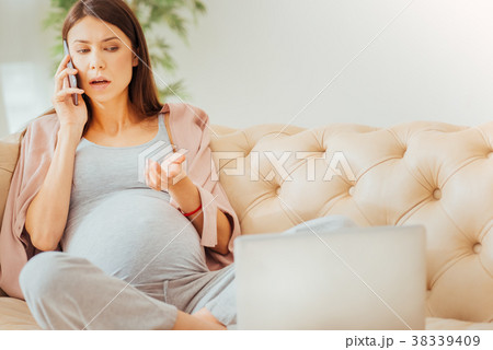 Serious occupied woman sitting and having phone 38339409