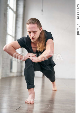 Young fit man stretching legs doing forward lunge. 38341429