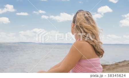 Beautiful woman is sitting on the beach. 38345624