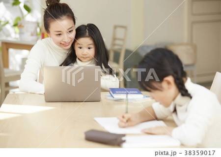 リビングで仕事する母親と遊ぶ子供の写真素材