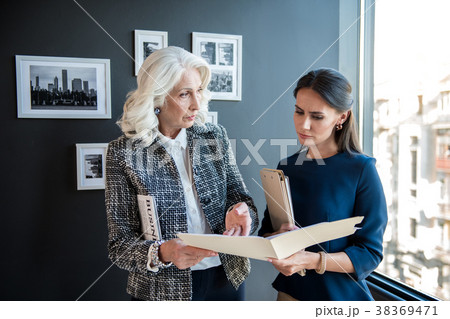 Serious stylish aged female is standing with her Serious stylish aged female is standing with her 38369471