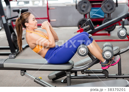 Asian woman doing sit-ups on bench in gym Asian woman doing sit-ups on bench in gym 38370201