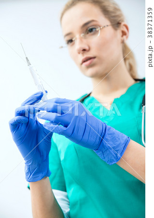 Female vet prepares syringe to injection. Female vet prepares syringe to injection. 38371359