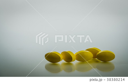 Yellow oval tablet pills on white background  38380214